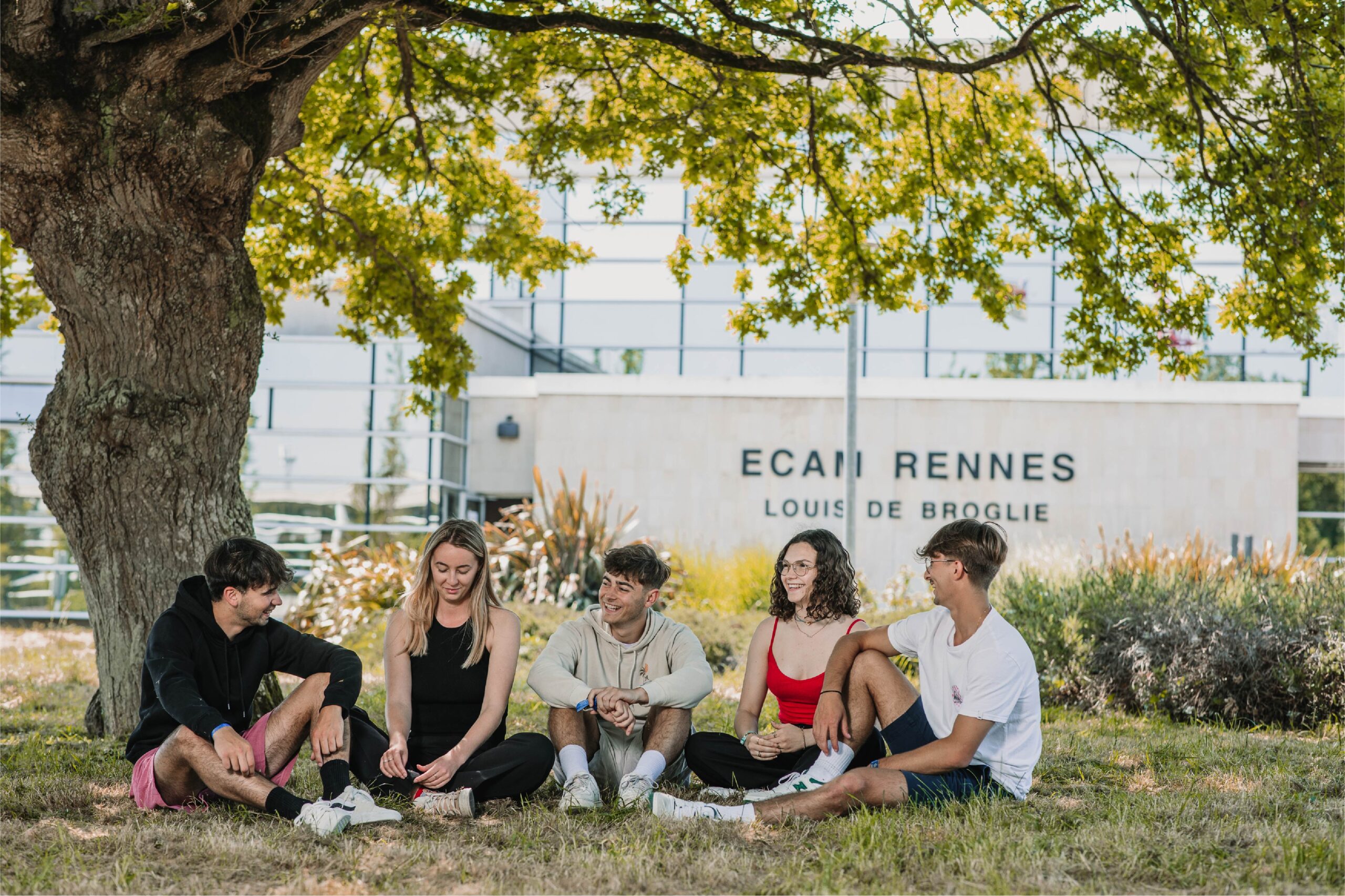 Groupe d'étudiant qui discute dans l'herbe devant l'ECAM Louis de Broglie. vie étudiante